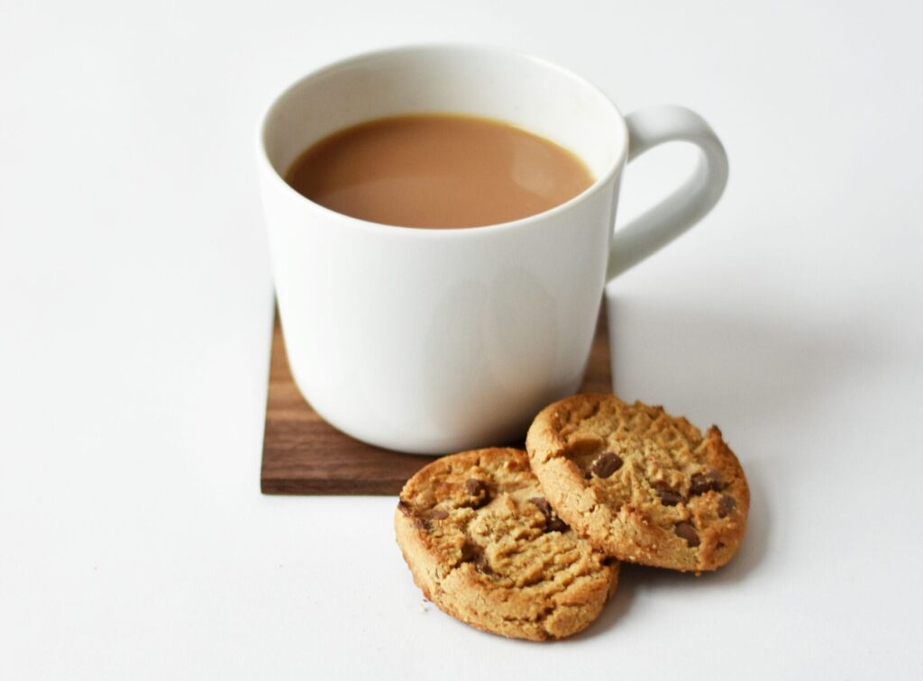 white ceramic coffee mug beside cookies