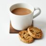 white ceramic coffee mug beside cookies