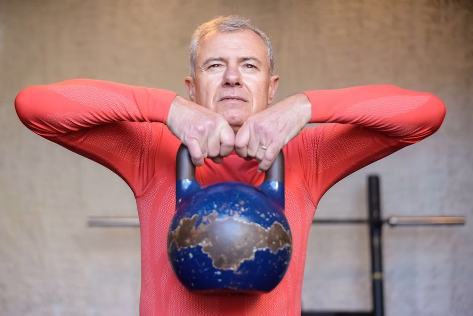 senior woman lifting kettlebell weights indoors Saúde e Bem-estar